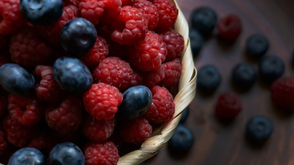 Raspberries and blueberries on the background of pottery. Black and red berries.