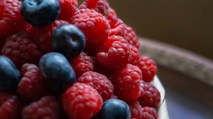 Raspberries and blueberries on the background of pottery. Black and red berries.
