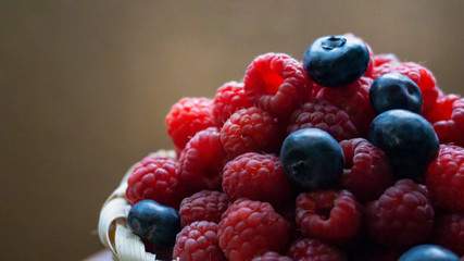 Raspberries and blueberries on the background of pottery. Black and red berries.