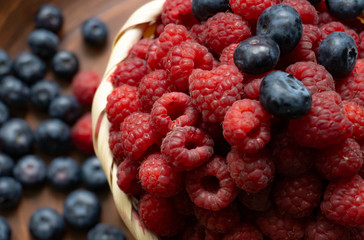 Raspberries and blueberries on the background of pottery. Black and red berries.