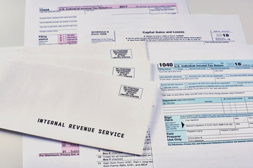 Three mails from the Internal Revenue Service lie on 1040, Schedule D form 1040 and 1040a tax forms