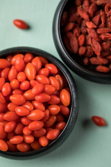 Frische und getrocknete Goji-Beeren Superfood in schwarzer Porzellan Schale auf Mint Grün Pastell...