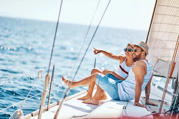 Fototapeten Romantic man and woman spending time together and relaxing on yacht. © luckybusiness