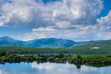 Montenegro, Glassy water of lake krupac, an artificial lake near niksic city inside green forest nature landscape surrounded by mountains under blue sky with clouds