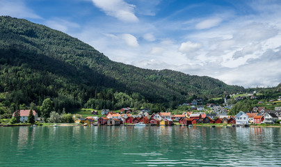 Fototapeta na wymiar Panoramic view from the fjord at Solvorn, a cute small resort village pressed between mountains on the western shore of the Lustrafjorden (innermost part of the Sognefjorden). Midsummer day in Norway.