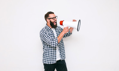 Fashion portrait of emotional hipster man with megaphone on white background in stylish sunglasses....