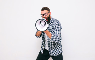 Fashion portrait of emotional hipster man with megaphone on white background in stylish sunglasses....