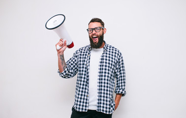 Fashion portrait of emotional hipster man with megaphone on white background in stylish sunglasses. Sales man using megaphone yelling