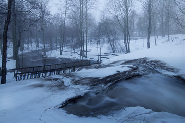 Park with river flowing shrouded in mist 