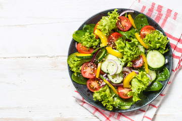 Fresh vegetables salad on white wooden table.