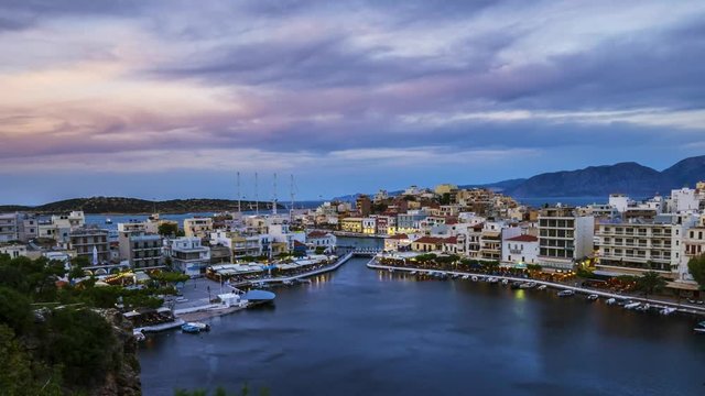 View of beautiful sunset over Lake Voulismeni at Agios Nikolaos, island of Crete, Greece - timelapse, zoom out, tilt 