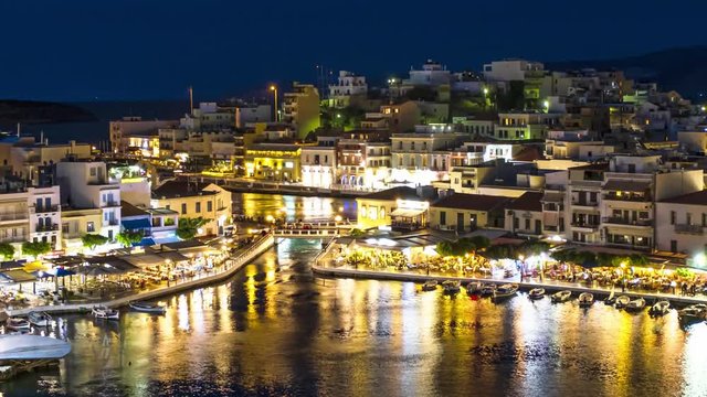 Night view over Lake Voulismeni at Agios Nikolaos, island of Crete, Greece - timelapse, zoom out, tilt 