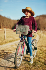 Fototapeta na wymiar Cute little ten year old girl riding bicycle on countryside.