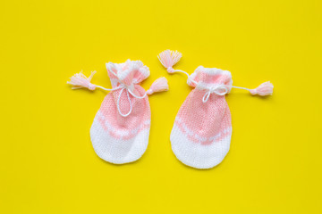 Baby gloves on yellow background.