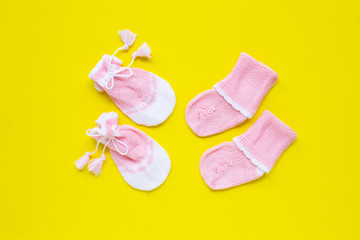 Baby gloves and socks on yellow background.