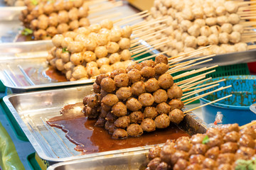 Grilled meatball topping with sweet chilli sauce in street food market. Picture with grain and color from film simulation filter. Picture with selective focus and close up view.