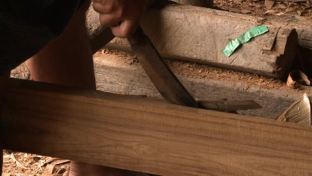 A close up shot of the rough edges of a long piece of wood being cut by a cutlass