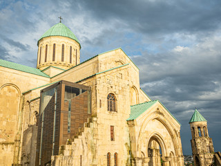 Bagrati Cathedral and its belfry in the evening against dark clouds