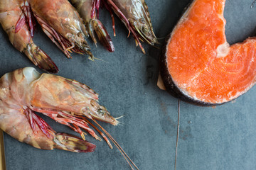 Fresh salmon fish with sea prawn shrimp on black plate, Seafood