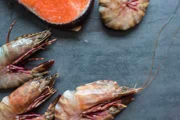 Fresh salmon fish with sea prawn shrimp on black plate, Seafood
