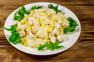 Festive salad with chicken breast, sweet corn, canned pineapple and mayonnaise on wooden table