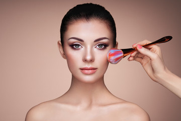 Beautiful Woman applies Skin Tone with Brush. Beautiful Woman face. Perfect Makeup. Skincare...