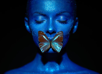 Mannequinvrouw in blauwe heldere fonkelingen en neonlichten die in studio stellen. Portret van mooie sexy vrouw met blauwe vlinder. Art design kleurrijke glitter gloeiende make-up