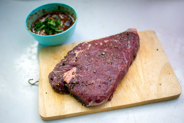Raw beef steak cooking by seasoning such as salt and black pepper on wood plate for grill with Thai spicy dipping sauce. Homemade cooking beef steak local Thai style recipe's.