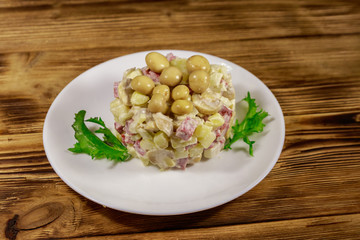 Potato salad with marinated mushrooms, sausage, onion and mayonnaise on wooden table