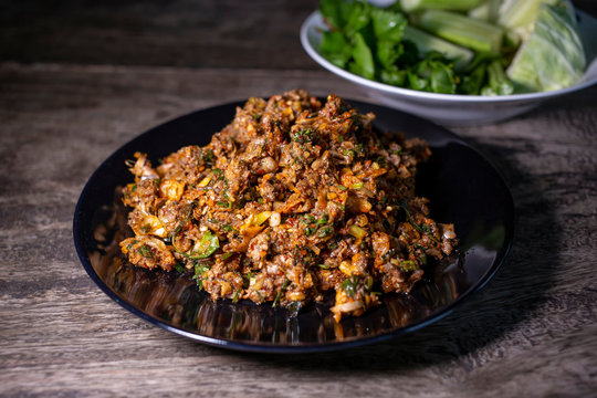 Spicy duck minced salad on wood table with fresh vegetables. Thai local food recipe Larb Ped delicious menu.