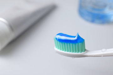 Toothbrush with water drop and toothpaste on blurred background