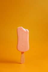 pink ice cream popsicle on yellow background bitten off a piece