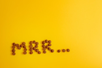 cat food on yellow background laid out in word of cat purring, Mrr top view