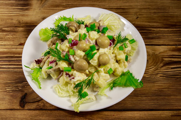 Potato salad with marinated mushrooms, eggs, red onion and mayonnaise on wooden table