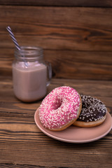 A plate with donuts and a glass mug of coffee on a wooden background. Coffee break.  Vertical. Close-up