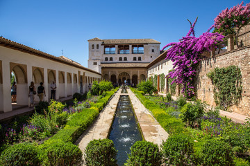 Fototapeta na wymiar Granada, Andalucia / Spain »; July 2018: Water jets in the gardens of Generalife Alhambra with the building in the background