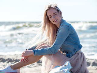 Fototapeta na wymiar Young cheerful girl on the seashore. Young blonde woman smiling. Young cheerful woman on a walk