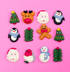 Sugar glaze figurines for Christmas decoration. Christmas food decorations.  Christmas symbols. Christmas cookies on pink background from above. Desert.