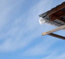 metal roof angle with snow against blue sky with clouds