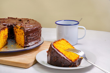Freshly baked yellow homemade cake with chocolate glaze on the top. Vegan cake with chocolate glaze, close up. Peace of cake and fork.