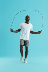 Workout. Sports man in sportswear exercising on jumping rope - obrazy, fototapety, plakaty