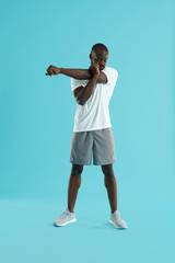 Fototapeta na wymiar Workout. Man stretching arm, warming up on blue background