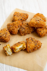 Fried camembert on a baking sheet on a white wooden background, side view. Close-up.