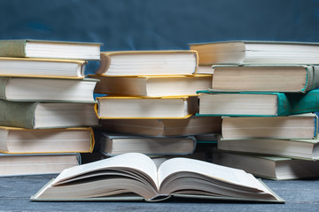 The open book lies on the Desk against the background of old textbooks. The concept of the school year.