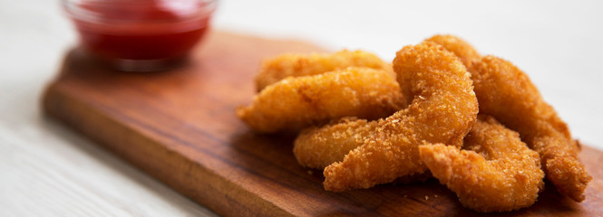 Fried shrimps tempura with ketchup on a rustic wooden board, side view. Close-up.