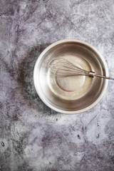 Metal bowl and beater whisk. Kitchen utensils. Eco friendly Zero waste plastic free kitchen on gray  background. concept sustainable lifestyle or Recycling and ecology.