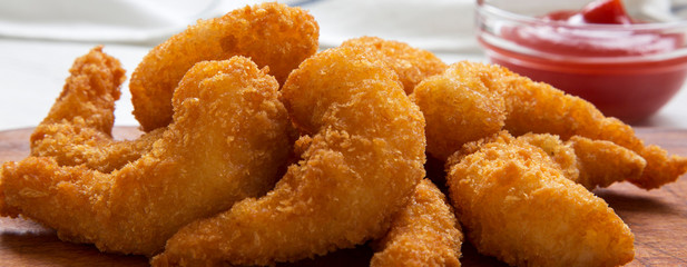 Fried shrimps tempura with ketchup on a rustic wooden board, side view. Close-up.