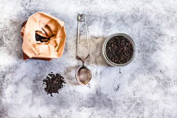Black tea and tea infuser in a jar and a paper bag. Zero waste plastic free kitchen on gray  background. concept sustainable lifestyle or Recycling and ecology