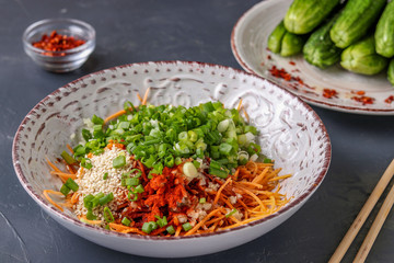 Preparing products for cooking traditional Korean cucumber kimchi snack: mixing ingredients in a bowl, fermented food, horizontal photo