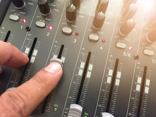 The male hand makes the sound adjustment on the audio mixer - obrazy, fototapety, plakaty